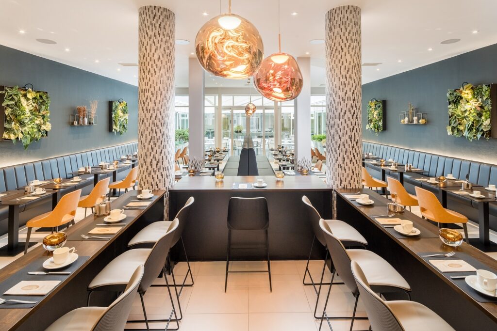 Rundumblick im Atrium im Parkhotel Kronsberg, schwarze, gedeckte Tische, aufgestellt in U-Form, ballförmige Deckenleuchten in der Mitte, hell und einladend