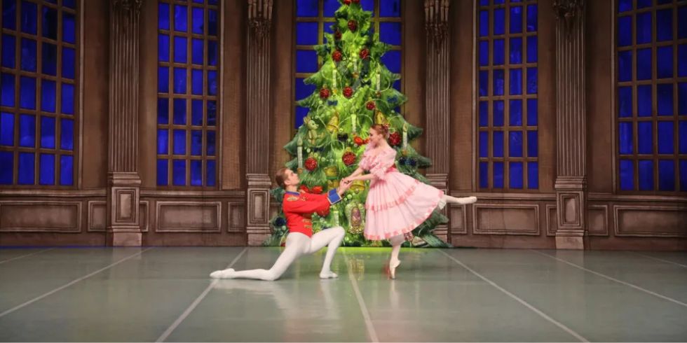 两名芭蕾舞演员在装饰一新的圣诞树前表演《胡桃夹子》中的一幕。