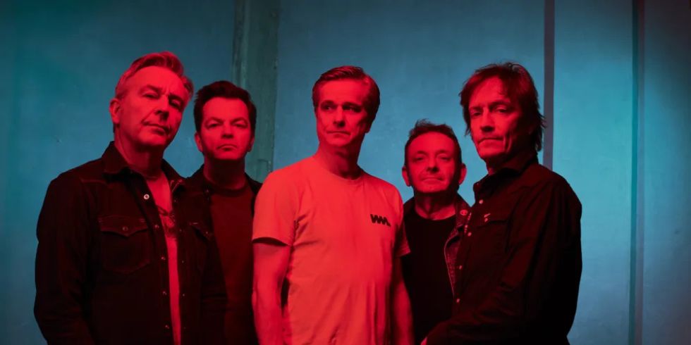 在一个蓝红相间的房间里，五个人相邻而立，严肃地看着镜头。