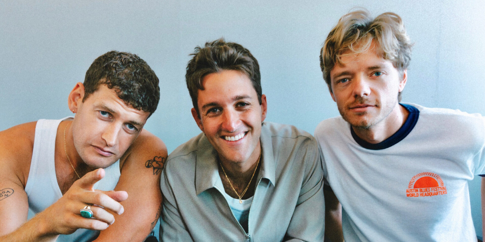 三个年轻人相邻而坐，对着镜头轻松地微笑。