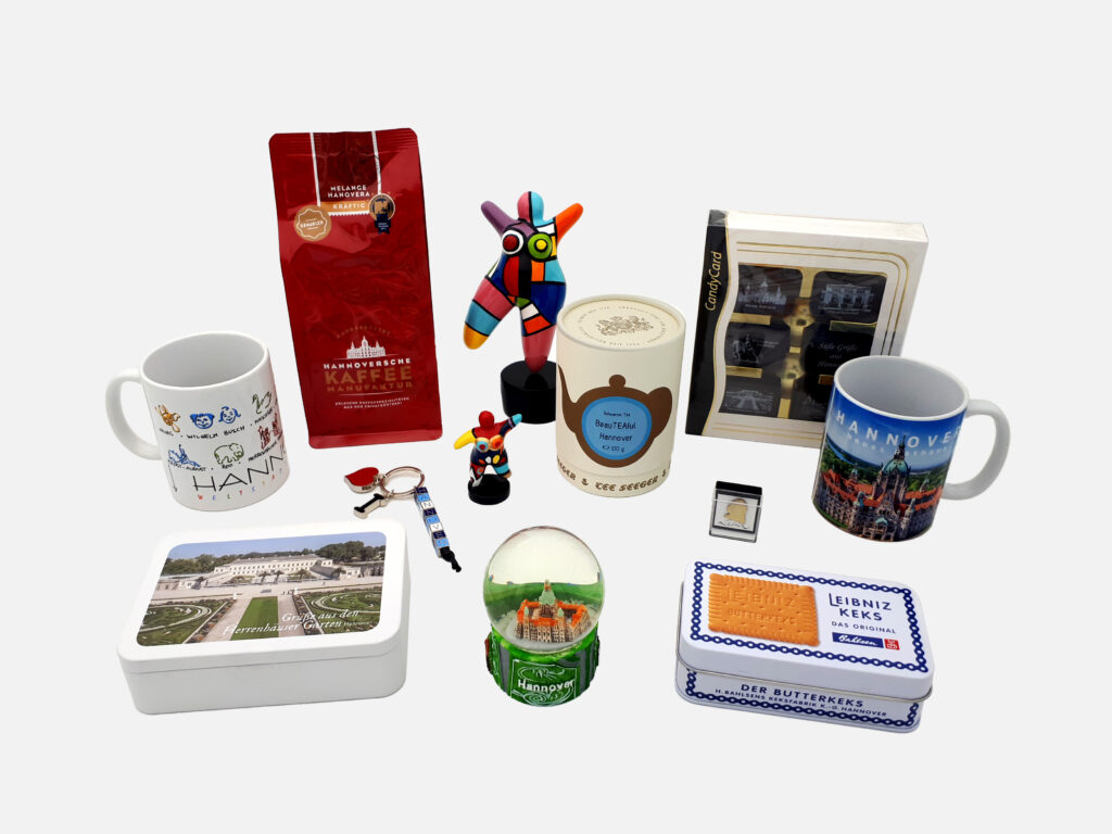 Souvenir-Auswahl aus Hannover mit Tassen, Kaffee, Süßwaren, Figuren, Schneekugel und Schlüsselanhänger